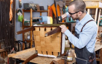 Qualified workman upholstering chair in repair furniture workshop